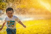 Niño jugando en el agua de un aspesor.