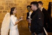 Una voluntaria de Nightfever disfrazada de ángel invita a chicos disfrazados de zombi a poner una vela en la iglesia
