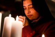 Una joven reza con velas y el rosario, foto de Gianna B para Unsplash