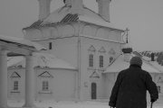 Una mujer anciana camina junto a una iglesia ortodoxa rusa nevada.