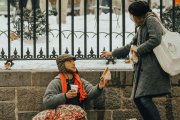 Una mujer da limosna a un hombre en la calle nevada.