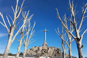 La cruz del Valle de los Caídos se alza sobre los árboles desnudos de Cuelgamuros, símbolo de un lugar donde se cruzan memoria, fe y batalla cultural.