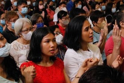 Filipinos en misa rezan con las manos levantadas el Padrenuestro