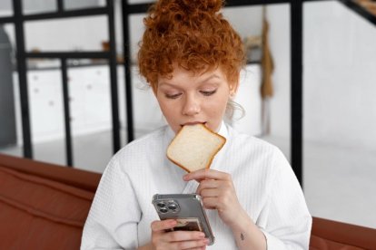 Una chica comiendo con un teléfono.