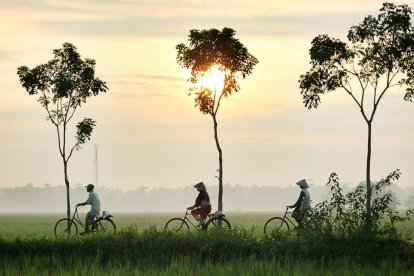 Tres personas en bicicleta en el amanecer