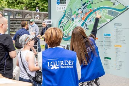 Unos voluntarios indican direcciones a peregrinos en el Santuario de Lourdes