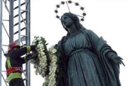 Un bombero de Roma deposita una corona de flores en lo alto del monumento a la Inmaculada