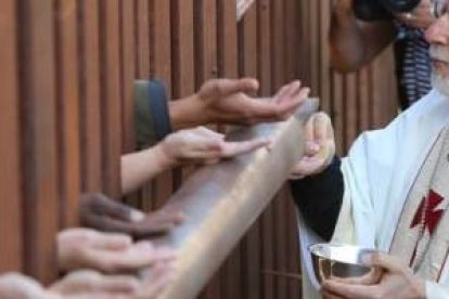 El obispo de Tucson reparte la comunión desde el lado de EEUU a los fieles que siguieron la misa en el lado mexicano