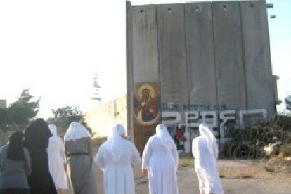 Unas religiosas católicas pasan junto al muro que tiene encajonados a los habitantes de Belén