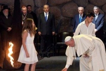 Francisco y dos jóvenes católicos vestidos de blanco ofrecen unas flores en la Sala Memorial de Yad Vashem