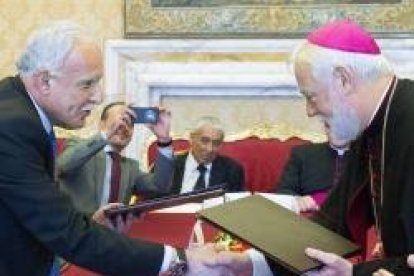 Monseñor Gallagher y el palestino Al-Malki intercambian las copias del acuerdo firmado