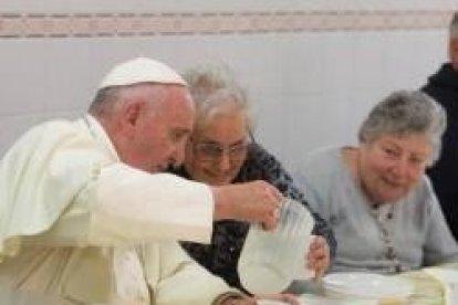 El Papa Francisco sirve el agua a una compañera de mesa en el comedor de Cáritas Florencia