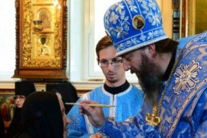 En la fiesta del icono de Kazán, un obispo ortodoxo bendice con un pincel en agua bendita a unas religiosas - a la izquierda, el icono preside la ceremonia