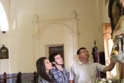 La imagen representa a la Virgen cargada con comida en la bolsa y al niño en el otro brazo.