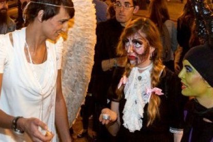 Night Fever en noche de Halloween en Valencia - Una evangelizadora vestida de ángel invita a orar con velitas en la iglesia a jóvenes vestidos de zombis