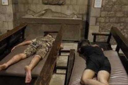 Dos menores duermen en los bancos de Santa Anna, junto a la tumba del caballero Miquel de Boera, del siglo XVI