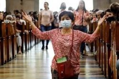 Una mujer reza en una iglesia de Asia... pero en varios países ya no es posible hacerlo en misa... Singapur e Italia, por ejemplo, y ahora Malasia