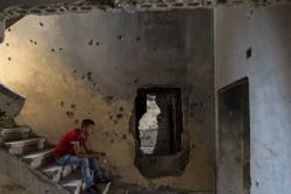 Estudiante cristiano rezando el Rosario en un edificio destruído por la guerra en Siria. Foto (C) Ismael Martínez Sánchez/ACN