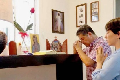 Una familia reza en su casa ante una imagen de la Virgen de Guadalupe