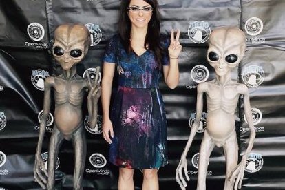 Una visitante del International Ufo Congress -que se celebra desde 1991- se fotografía con dos muñecos