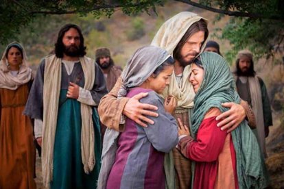 Fotograma de una película en la que Jesús abraza a Marta y María tras la muerte de Lázaro