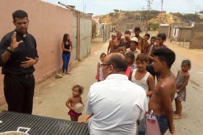 El padre Robinson, en la imagen bendiciendo una comida para las personas pobres que hacen cola