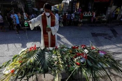 Sacerdote con mascarilla bendice palmas en el Domingo de Ramos de 2020, ya con mascarilla, en Filipinas