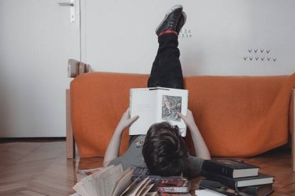 Un joven leyendo, quizá libros de Cuaresma, en una postura peculiar, en una foto de Anita Jankovic para Unsplash