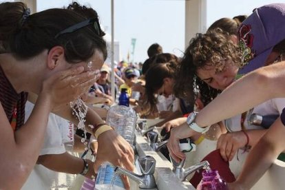 Peregrinos acalorados consiguen lavarse en uno de los escasos puntos de agua en el Parque del Tajo en la JMJ de Lisboa