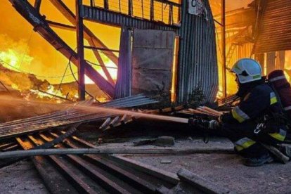 Un bombero sofoca las llamas de los almacenes de Cáritas destruidos tras un bombardeo.
