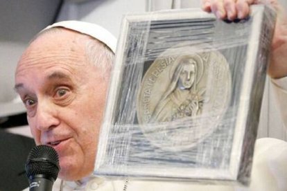 El Papa Francisco, en un viaje, muestra un grabado con la imagen de Santa Teresita de Lisieux