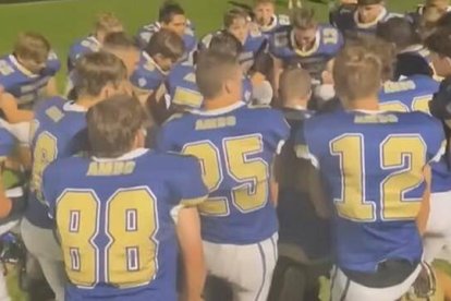 Una escena del vídeo que se viralizó, que muestra a los integrantes del equipo colegial de fútbol americano rodilla en tierra, rezando un avemaría antes del partido, según es su costumbre.