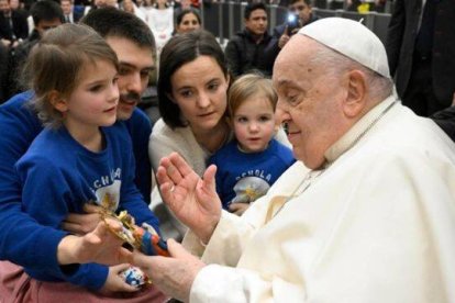 Francisco bendice una imagen del Niño Jesús al ser saludado por una familia presente en la audiencia. Foto: Vatican Media.
