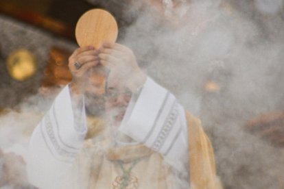 Un sacerdote eleva la Sagrada Forma en la consagración.