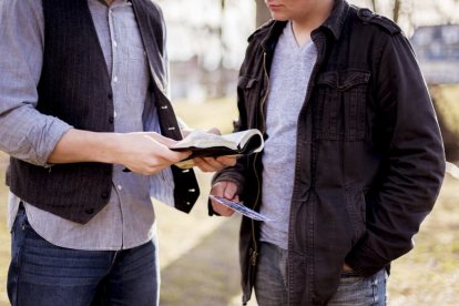 Un joven rezando con un adulto.