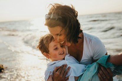 Madre e hijo juegan en el mar, y una luz los baña