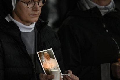 Unas religiosas rezan por el Papa Francisco, con velas y rosarios, de noche