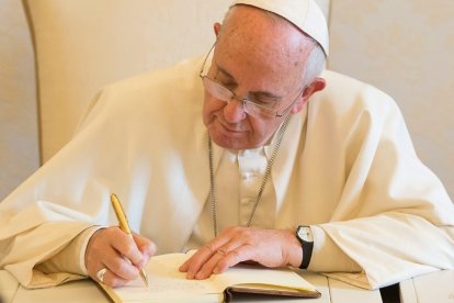 El Papa Francisco escribiendo.