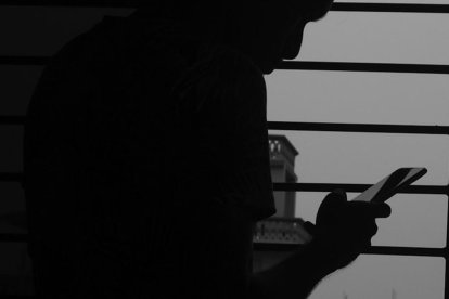 Un hombre mira el móvil a contraluz.