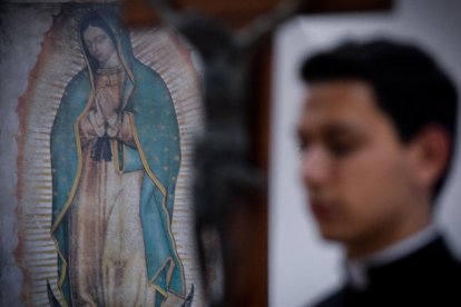 Un joven seminaristas lleva una cruz ante la Virgen de Guadalupe.