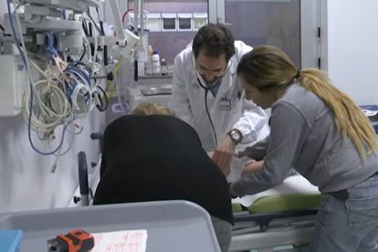 Un médico y otra persona atienden a un paciente en el hospital.