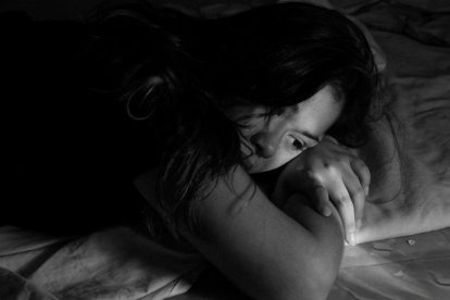 Mujer joven echada en la cama.