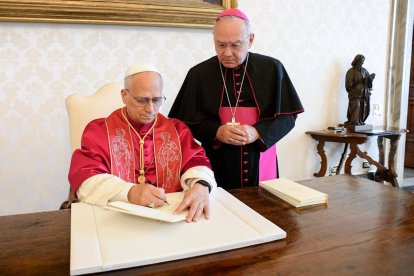 El Papa, firmando el documento en presencia de Edgar Peña Parra