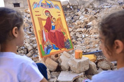 Unas niñas cristianas contemplan un icono de la Virgen entre las ruinas de Alepo (Siria).