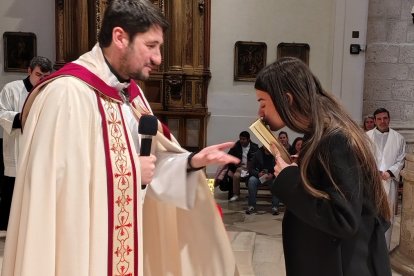 Una joven besa las Escrituras que ofrece el sacerdote Jesús Úbeda, uno de los Ritos de Ingreso al catecumenado