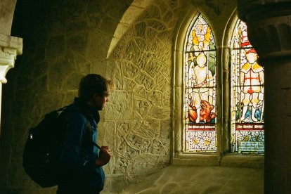 Un hombre en un laberinto oscuro busca la luz en las vidrieras, símbolo del deseo de libertad