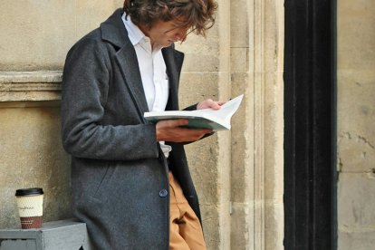 Un hombre fascinado con un libro, hasta olvida su café