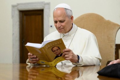 León XIV lee un libro publicado en el Vaticano que recoge sus mejores discursos como prior general de los agustinos.