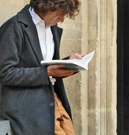 Un hombre fascinado con un libro, hasta olvida su café