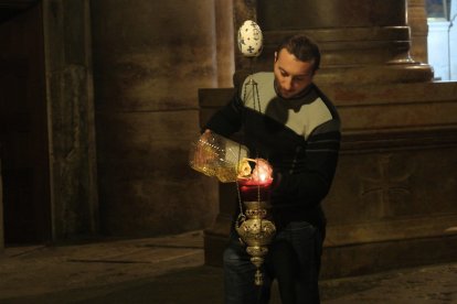Un operario rellena las lámparas del Santo Sepulcro durante la noche.